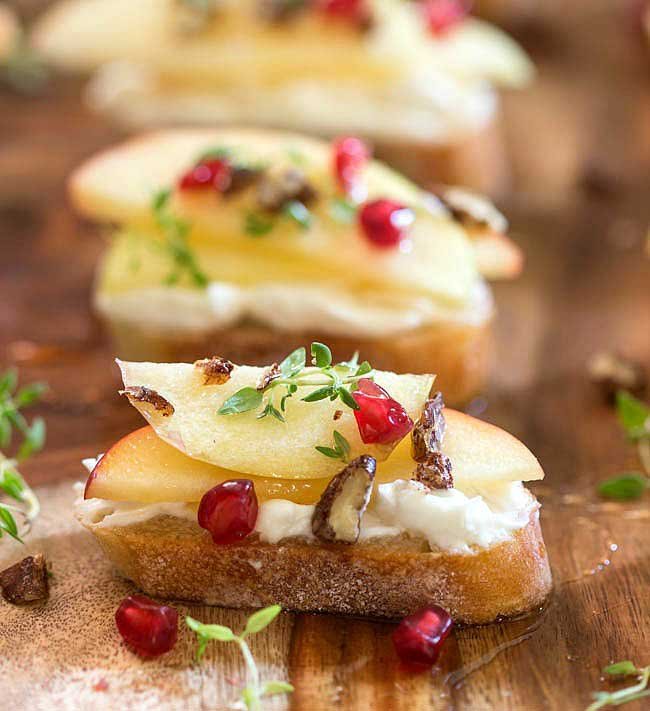 Goat Cheese Bruschetta topped with apples and pecans on a cutting board.