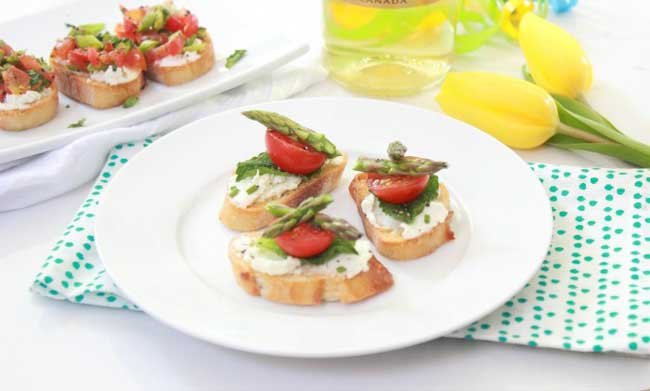 3 bruschetta's with mozzarella, asparagus and tomatoes on a white plate