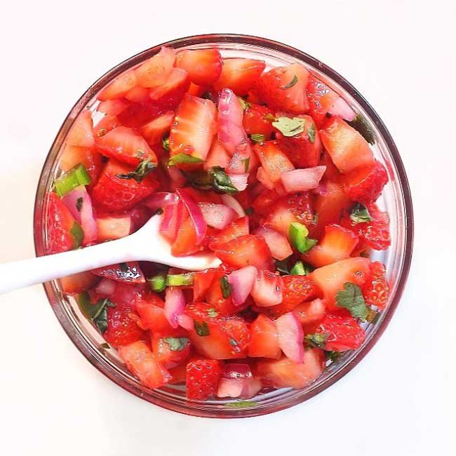 a closeup overhead shot of strawberry jalapeno salsa on a white background