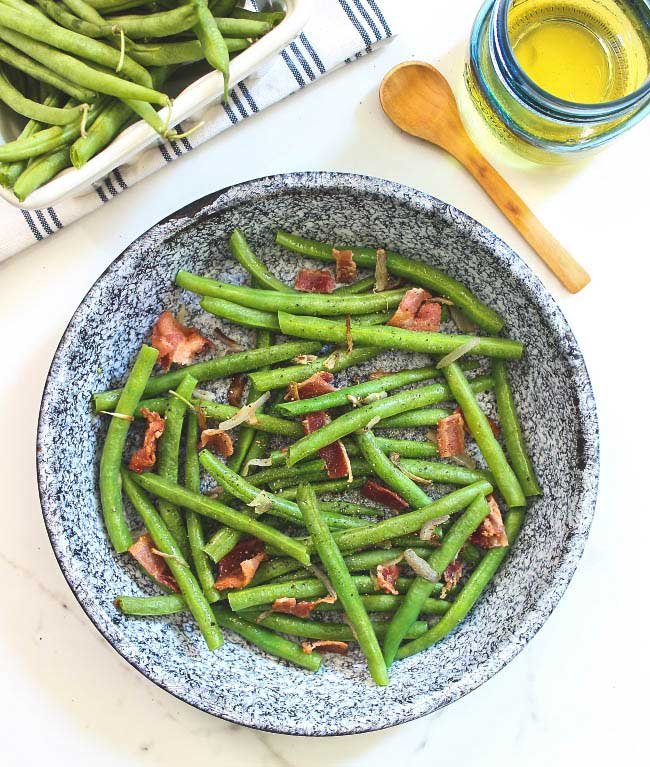 a bowl of green beans with bacon and shallots