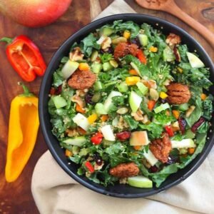 A black bowl filled with Autumn Kale Apple and Quinoa Salad.
