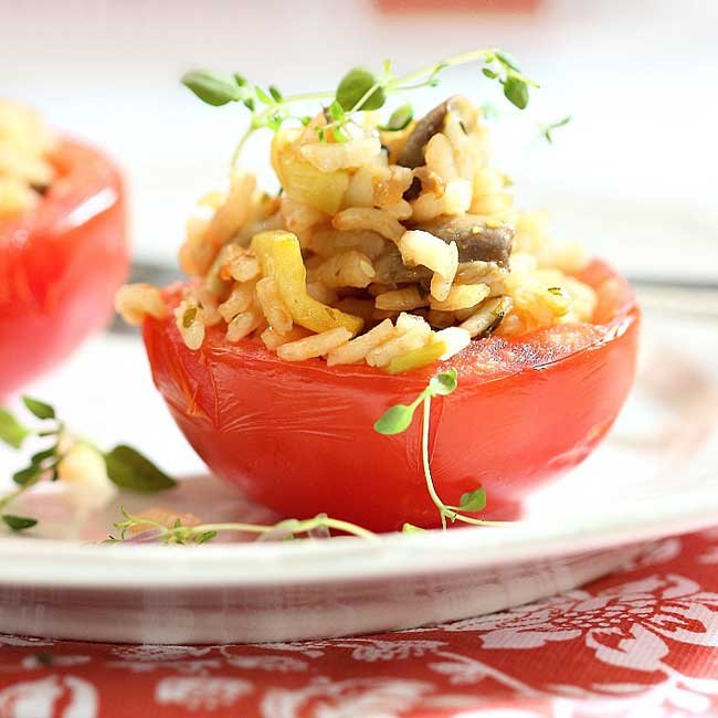 side view of 1 risotto stuffed tomatoe on a while plate