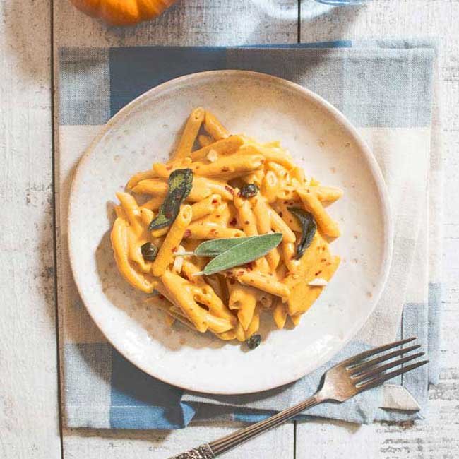 overhead shot of vegan pumpkin pasta on a served dish with cutlery