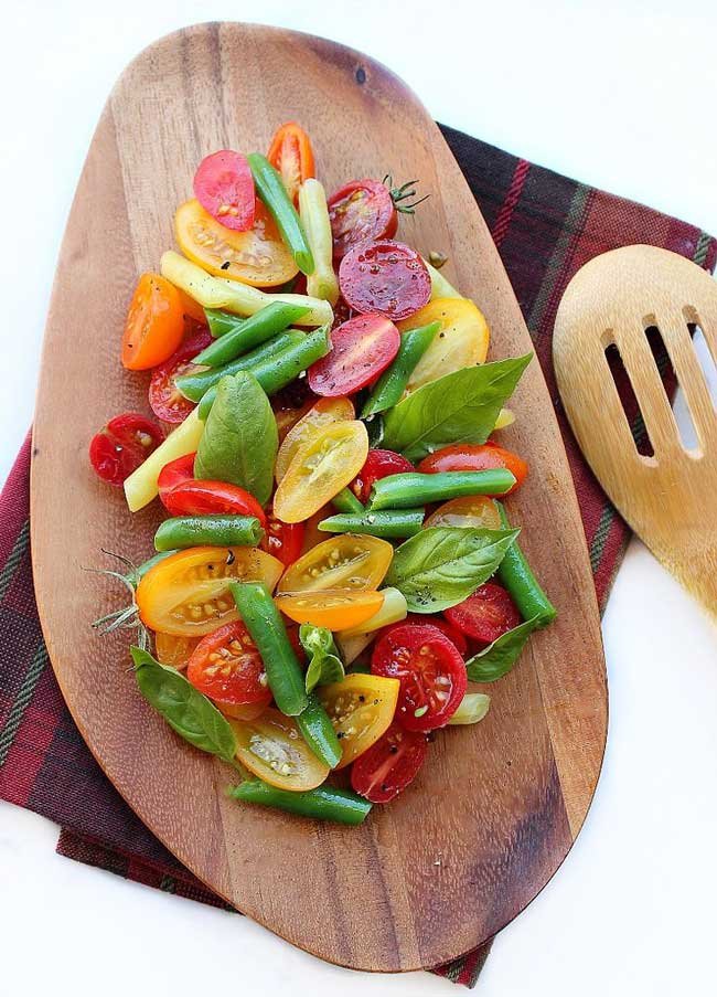 tomato basil salad with green beans on a wooden oval shaped plate