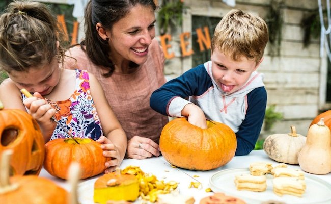 Kids decorating small pumpkins with their mom.